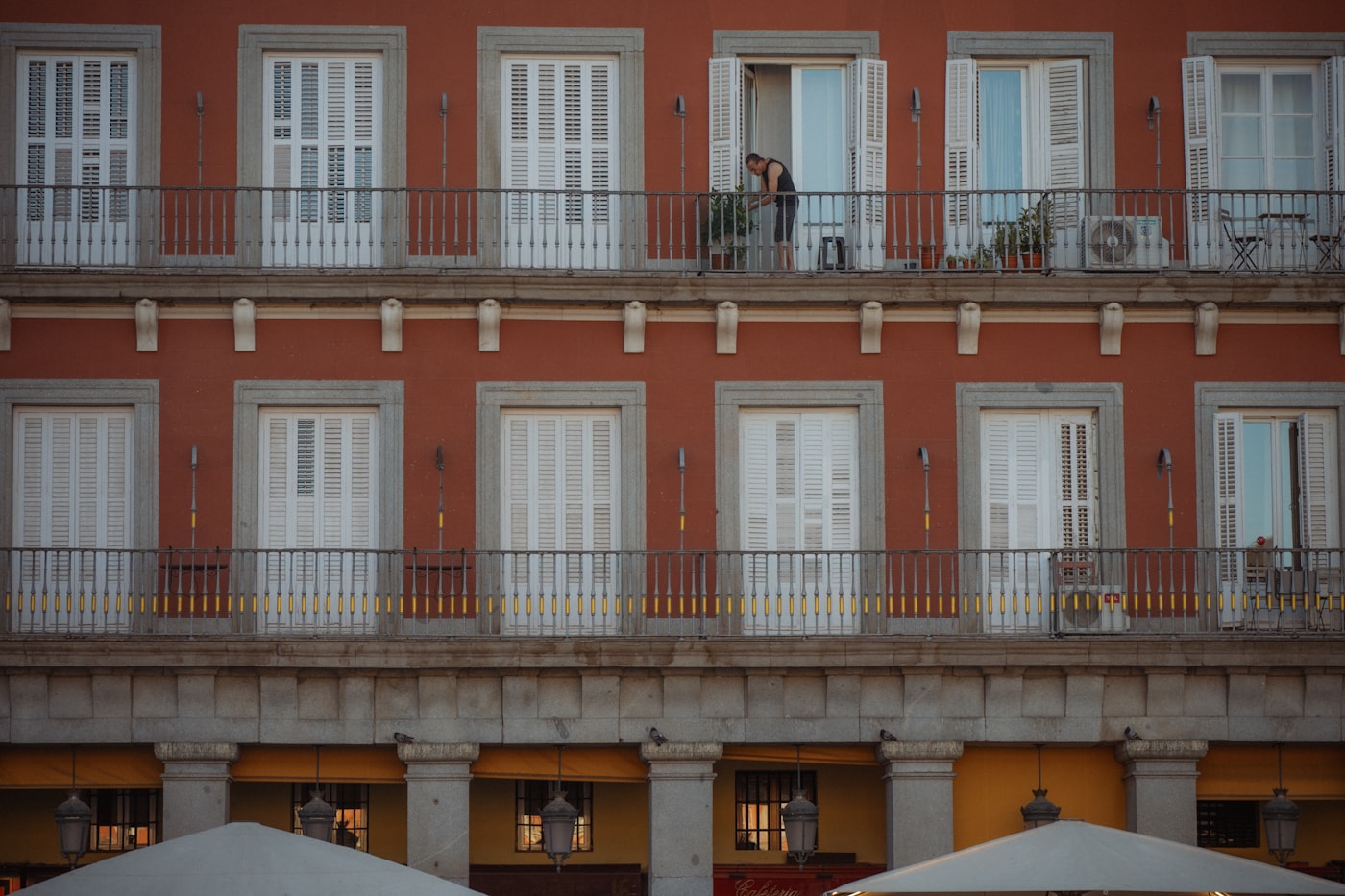 Dos personas charlando en un balcón de un edificio rojo de Madrid